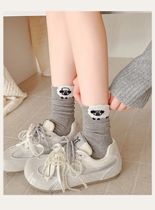 Close-up of grey knit mid-calf socks featuring a cute cartoon sheep embroidery detail