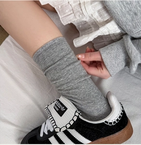 Nahaufnahme grauer Strick-Schoppen-Socken kombiniert mit klassisch-modischen Sneakern