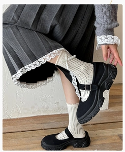 Detail of beige polka dot socks with white lace trim and black Mary Jane platform shoes