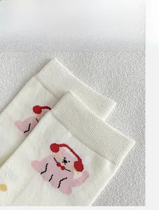 Dettaglio di calzini bianchi in cotone a costine con ricamo di un simpatico cucciolo rosa