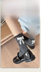 Detail of dark grey crew socks with lace bows, pearls and ruffle edges on wood floor