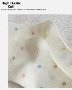 Dettaglio del polsino a coste elasticizzato su calze bianche con pois colorati