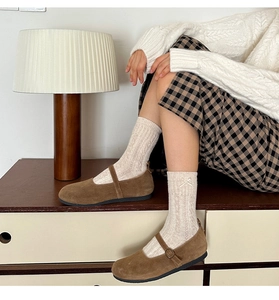 Détail de chaussures Mary Jane en daim marron avec chaussettes en maille torsadée