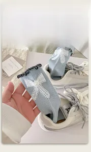 Detail of light blue knit sock with white lace bow and pearl accent on the wavy cuff