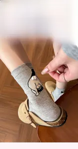 Close-up of gray cotton socks featuring a cute cartoon cat print and 3D white pom-pom tail