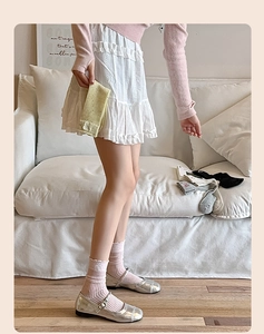 Detail von rosa Rüschensocken kombiniert mit silbernen Mary Janes und einem weißen Spitzenkleid