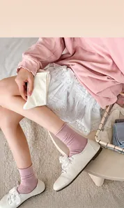 Detail van roze geribbelde sokken met reliëf strik en kanten rok in balletstijl