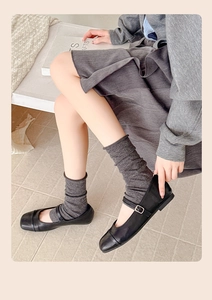 Dettaglio degli scaldamuscoli in maglia grigio scuro con scarpe Mary Jane nere eleganti