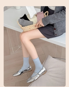 Close-up of ballet-style bow socks with ribbon detail and silver Mary Jane shoes
