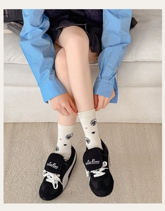 Detail view of milk white mid-calf socks with cute cartoon sheep and pink heart patterns