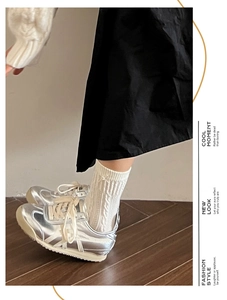 Gros plan de baskets argentées métallisées avec des chaussettes blanches à torsades