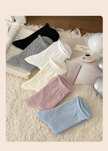 Detail of knit socks with relief bow patterns in various colors on a plush white rug