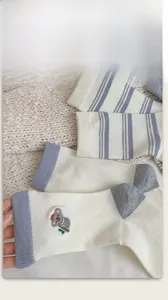 Detail of wool socks showing koala embroidery and striped knit texture on white fabric