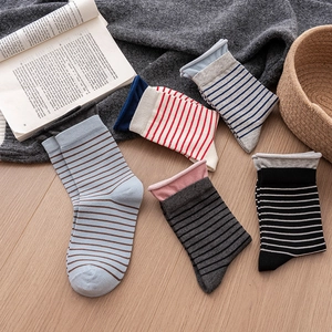 Five pairs of striped cotton crew socks in mixed colors on a cozy wooden floor