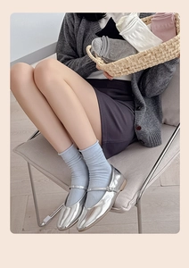 Detail of silver Mary Jane shoes with light blue rib-knit mid-calf bow socks