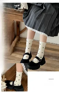 Macro detail of white ribbed knee-high socks with small black bow embroidery and lace trim