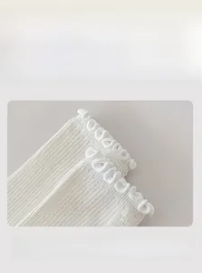 Detail of white ribbed knit sock cuff featuring ruffled edges and high-elasticity band