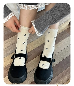 Close-up of cream bow-print crew socks with frill cuffs and black Mary Jane platform shoes