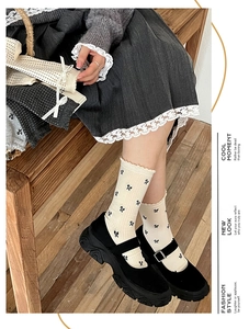 Detail of cream calf socks with black bow patterns and ruffled edge with Mary Jane shoes