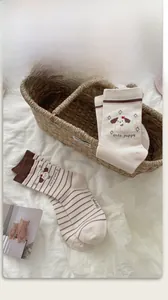 Detail of cute puppy embroidery on beige cotton blend mid-calf socks with striped trim
