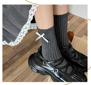 Detail of dark grey crew socks with white polka dot texture and side ribbon bow