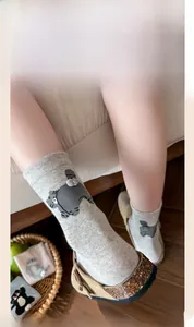 Detail view of cotton crew socks with grey cartoon cat pattern and ribbed cuffs