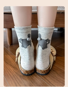 Close-up of grey knit socks featuring a 3D cartoon cat tail design on the heel