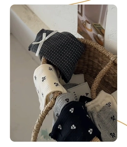 Macro detail of knit crew socks with bows and patterns in a vintage woven basket