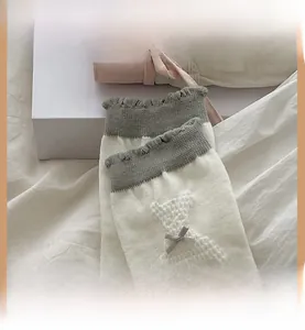 Détail de chaussettes tricotées avec motif d'ours en relief et nœud papillon gris