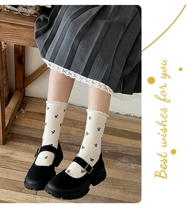 Close-up of bow-patterned calf socks paired with black platform Mary Jane shoes