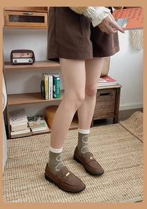 Close-up of olive green patterned mid-tube socks with brown loafers and corduroy shorts