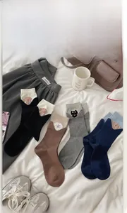Detail view of cotton crew socks in four colors with cartoon animal embroidery and fold-over cuffs
