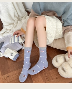 Detail of wool socks featuring cute koala embroidery and rib cuffs in a cozy home setting