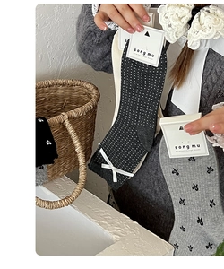 Detail of grey and black polka dot socks with white bow accents in branded packaging