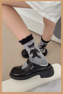 Détail de chaussettes grises avec motif d'ours en 3D et bordure en dentelle noire sur Mary Jane