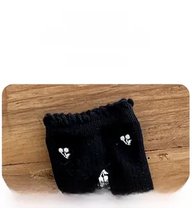 Detailed macro view of the ribbed cuffs and white floral patterns on black knit socks