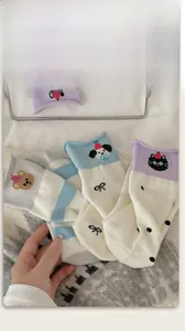 Detail of knitted mid-calf socks showing blue stripes, cat patterns, and cute bow accents