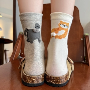 Cute cartoon cat socks with 3D plush tails in grey and cream on a warm indoor background
