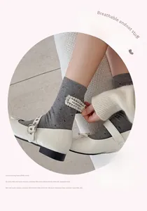 Close-up of gray polka dot mid-tube socks with white lace brand label and Mary Janes