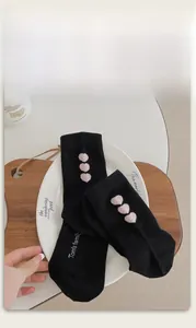 Detailed view of black mid-calf cotton socks featuring three pink flocked hearts and logo