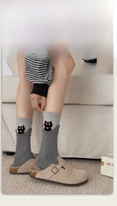 Detail of dark grey crew socks with cute black cat embroidery and wavy rolled cuffs