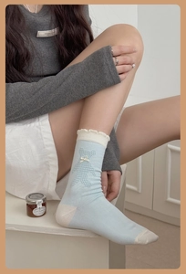 Détail de chaussettes bleu clair avec bords à volants, nœud 3D et motifs d'ours