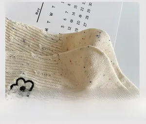 Close-up of beige knit socks with colorful flecks and reinforced heel detail