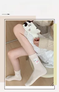 Détail d'une chaussette en coton crème avec broderie de chiot mignon et texture côtelée