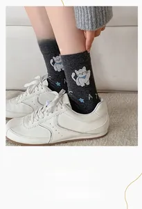 Detail of grey knitted socks featuring a cute white cat pattern and elastic cuff
