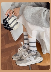Close-up of stylish striped crew socks worn with retro sneakers on a wooden floor