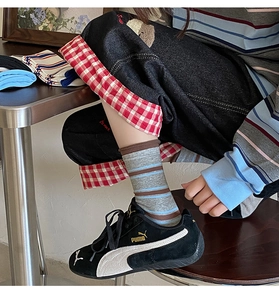 Dettaglio di calzini a righe colorate con denim vintage e scarpe da ginnastica nere