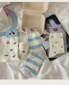 Detail view of cute animal embroidered socks with ruffles and bowknots on white fabric