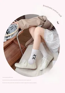 Détail d'une chaussette blanche en coton avec broderie XX noire et bordure en dentelle