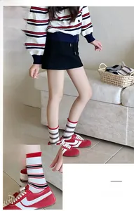 Dettaglio di calzini bianchi a metà polpaccio con strisce rosse e nere dal look alla moda